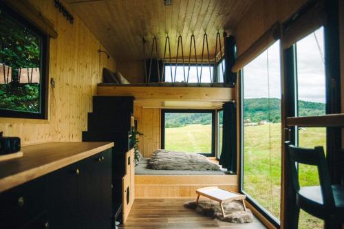 ein Schlafzimmer in einem winzigen Haus mit einem großen Fenster in der Unterkunft Včelín Müslivna in Jablonné v Podještědí