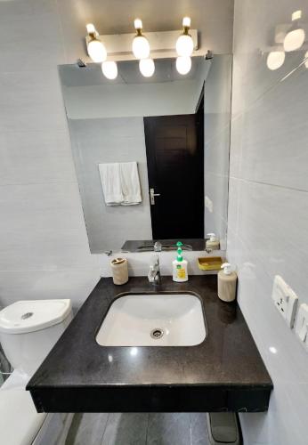 a bathroom with a sink and a toilet and a mirror at Two-Bedroom Luxury Apartment, Zameen Opal in Lahore