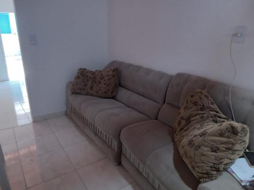 a couch in a living room with two pillows on it at Casa na Praia de Guaibim- Valença/Bahia in Guaibim