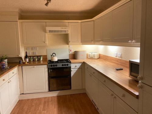 a kitchen with white cabinets and a stove at 2 Bedroomed Lodge with Private Garden in Penrith