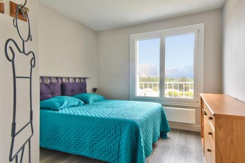 une chambre avec un lit avec une couette bleue et une fenêtre dans l'établissement Aux portes de l'océan à Saint-Jean-de-Monts, à Saint-Jean-de-Monts