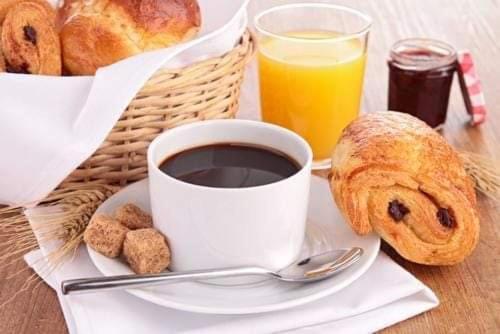 a cup of coffee and a basket of bread and orange juice at Péniche Morgane 2 chambre d'hôtes in Cambrai