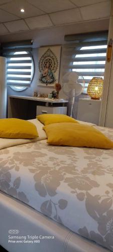 a bedroom with a large bed with yellow pillows at Péniche Morgane 2 chambre d'hôtes in Cambrai