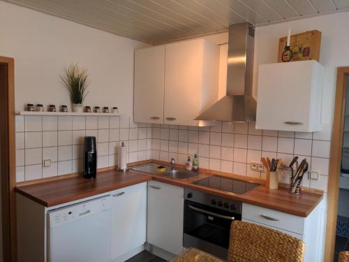 una cocina con armarios blancos y fregadero en Ferienwohnung im Grünen I, en Grebenstein
