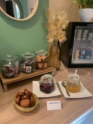 een tafel met potten honing en een bord eten bij Hôtel de Bretagne Dol centre ville - Hotel et Restaurant in Dol-de-Bretagne