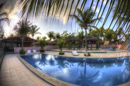 a swimming pool in a resort with palm trees at Pousada Sitio Phoenix in Prea