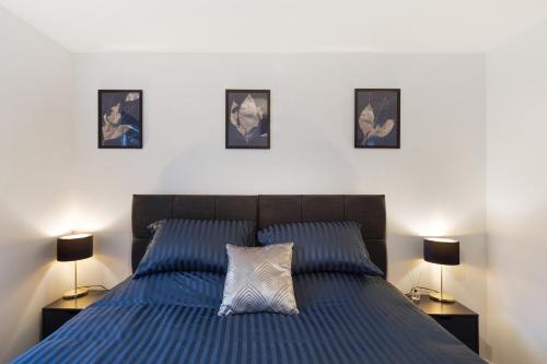 a bedroom with a blue bed with three pictures on the wall at Deluxe 2 bed flat w/free parking in High Wycombe