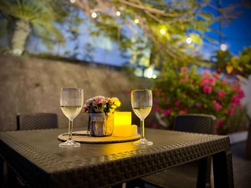 two glasses of wine on a table with flowers at Beach villa with cozy terrace in Río Hato