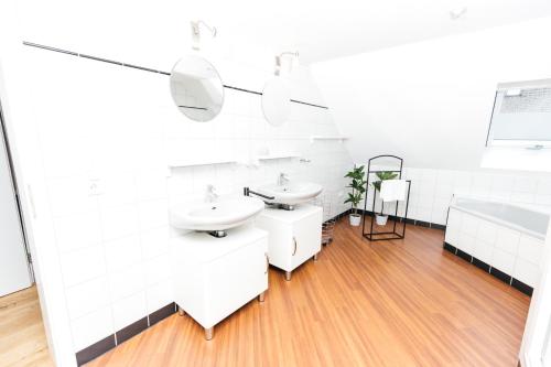 La salle de bains blanche est pourvue de 2 lavabos et d'une baignoire. dans l'établissement HEIMATEL - Ferienwohnung Bräuhaus, à Scheidegg
