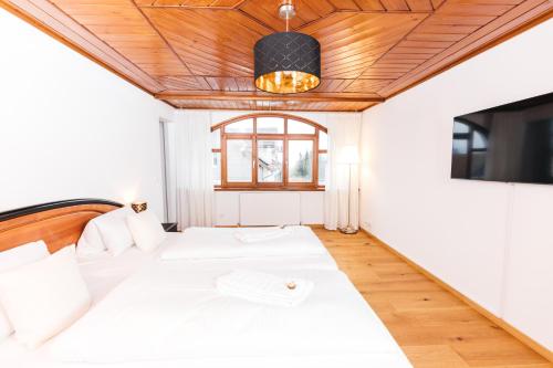 - une chambre avec un lit blanc et un plafond en bois dans l'établissement HEIMATEL - Ferienwohnung Bräuhaus, à Scheidegg