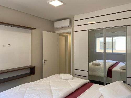 - une chambre avec un lit et un miroir dans l'établissement Apto em cond. c/piscina a 300m da praia DOV102, à Florianópolis