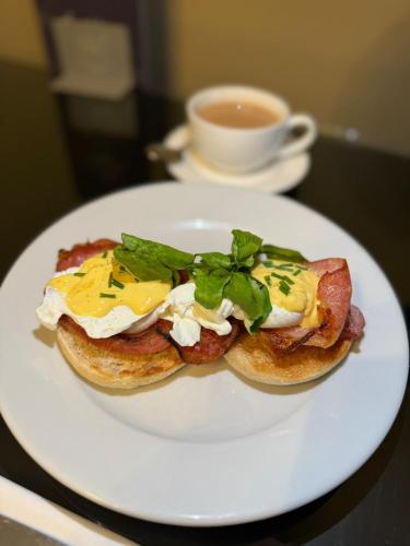 a white plate with a breakfast sandwich on a table with a cup of coffee at Stone Villa Chester in Chester