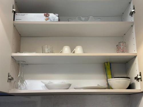 a white shelf with bowls and other items on it at The NADA APARTMENT of hope in Subotica