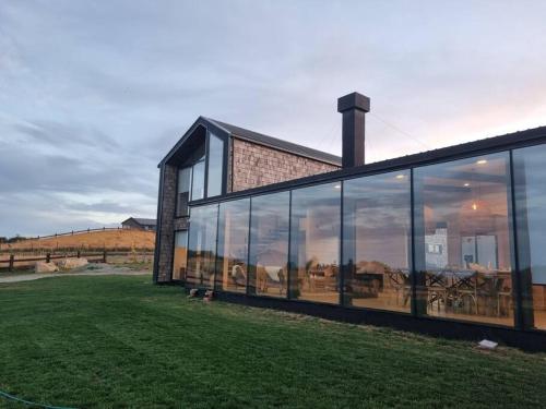 a building with large glass windows on a grass field at Casa de campo familiar, Puerto Varas Chile in Llanquihue