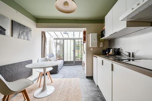 une cuisine avec des armoires blanches et une table et des chaises dans l'établissement L'Oasis Parisien - 2 pers - Métro Oberkampf, à Paris