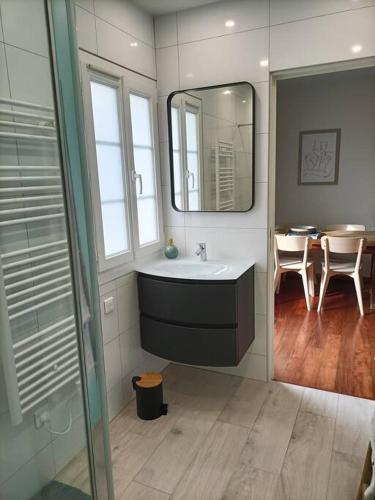 La salle de bains est pourvue d'un lavabo, d'un miroir et d'une table. dans l'établissement Maison de ville CDG, Villepinte, à Juilly