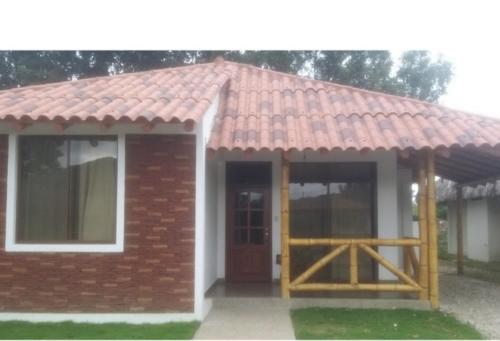 een klein huis met een rood dak en een houten deur bij PLAYA Y CAMPO EN UN SOLO LUGAR in Olón