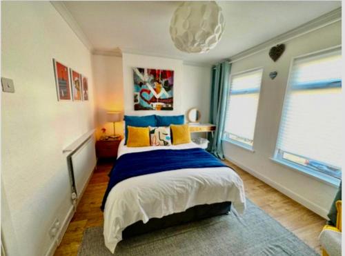 1 dormitorio con 1 cama con almohadas azules y amarillas en Bloom19 Traditional Belfast Entire House 10 mins from City Centre en Belfast