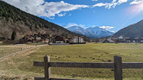 a wooden fence in a field with houses and mountains at Walliser Stadel in Fieschertal