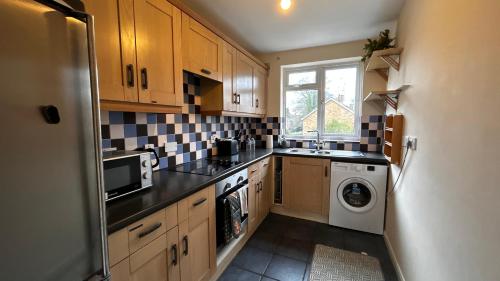 a small kitchen with a washer and dryer at Cozy 2 Bedroom Apartment close to Town Centre in Woking