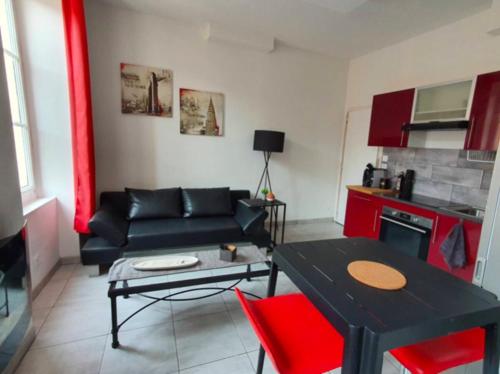 - un salon avec un canapé noir et des fauteuils rouges dans l'établissement Le 73 Bastide, à Carcassonne