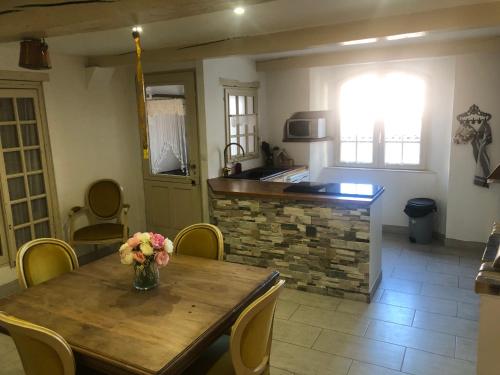 une cuisine avec une table en bois et un vase de fleurs. dans l'établissement Le choupisson, à Estoublon