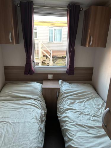two beds in a small room with a window at 3 BEDROOMED CARAVAN WITH AMAZING SEA VIEWS! in Scarborough