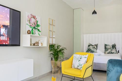 ein Schlafzimmer mit einem Bett und einem gelben Stuhl in der Unterkunft 31 on Forest Road (FatsoDelux) in Johannesburg