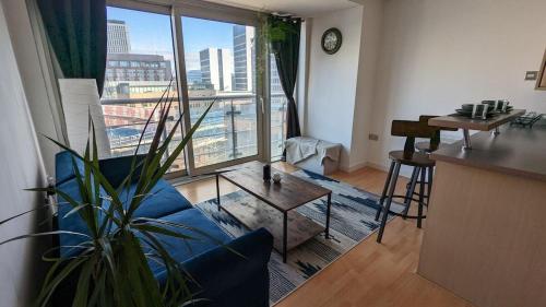 a living room with a blue couch and a large window at Excellent Leeds City Center 1 Bedroom Apartment in Leeds
