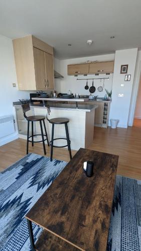 a kitchen with a wooden table and some bar stools at Excellent Leeds City Center 1 Bedroom Apartment in Leeds