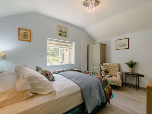 um quarto com uma cama, uma cadeira e uma janela em 2 Bed in Lixwm 88028 em Nannerch