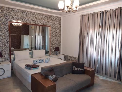 a bedroom with a bed and a couch and a mirror at Hospedaria Restaurante Xeque Mate in Luanda