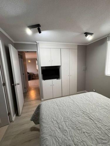 a bedroom with a bed and a flat screen tv at Moderno Departamento in Osorno