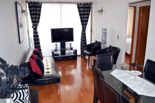 sala de estar con muebles de cuero negro y TV de pantalla plana en Departamentos Amoblados La Hermandad en Antofagasta