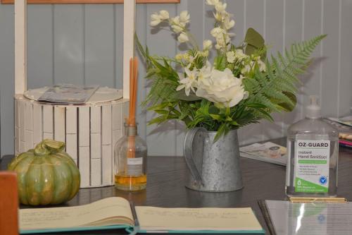 a table with a vase of flowers and a book at Land Of Lost Treasure in Maleny