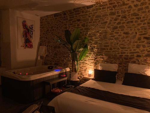 um quarto com uma cama e uma banheira ao lado de um quarto em Profitez d'une douce nuit avec jacuzzi em Fougères
