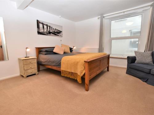a bedroom with a bed and a chair and a window at 3 Bed in Ilfracombe 66239 in Ilfracombe