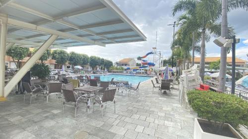 卡达斯诺瓦斯Apto 1 Suíte TOP - Pq aquático 24hs DiRoma Fiori的带桌椅的露台和游泳池