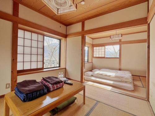 a room with two beds and a table and windows at 湯布院我楽珍民泊Yufuin Garakuchin in Yufuin