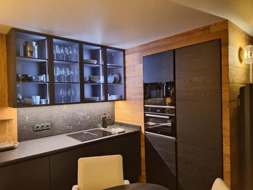 a kitchen with black cabinets and a sink at paisible appartement près des pistes in La Salle Les Alpes