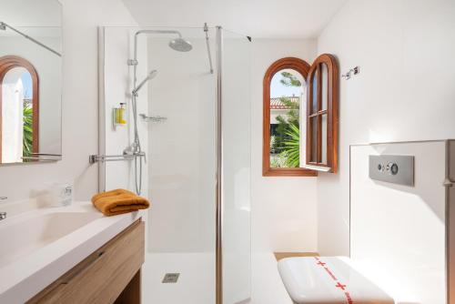 a white bathroom with a shower and a sink at SES ONES with sea views in Alcudia