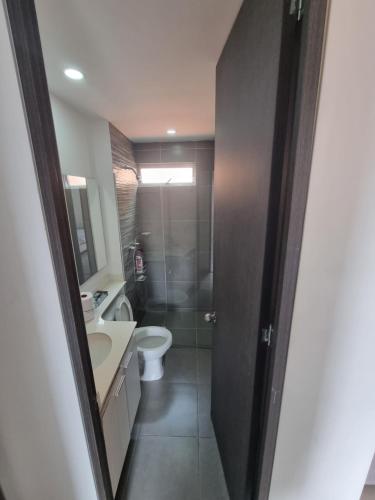 y baño con aseo, lavabo y ducha. en Cómodo apartamento, en Medellín