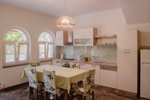 a kitchen with a table with chairs and a kitchen with white cabinets at Apartment Curri in Pučišća