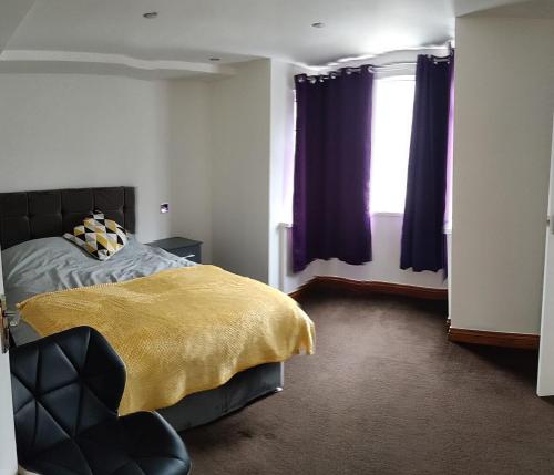 a bedroom with a bed with a yellow blanket and a window at Super 7Bed House - Hot Tub - Large Gathering Meets in Headingley