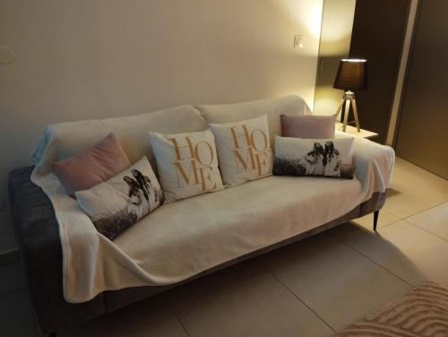 a couch with pillows with the word hug on it at Spacieux T2, Bord De Mer Sable Volcanique in Saint-Paul