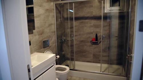 e bagno con doccia, servizi igienici e lavandino. di DEMİR OTEL a Burunabat