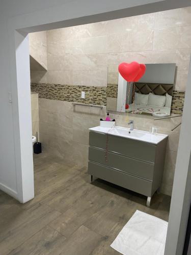 baño con lavabo y un globo cardiaco rojo en Empire Apartments Su 1 Celinastraat, en Paramaribo