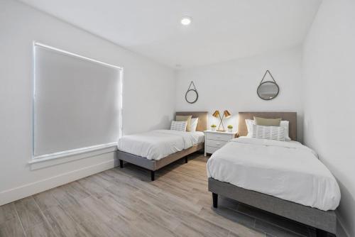 2 camas num quarto com paredes brancas e pisos em madeira em New! Few Minutes To Downtown, 10 To The Beach! em West Palm Beach