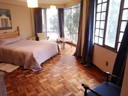 Schlafzimmer mit einem Bett, großen Fenstern und Holzböden in der Unterkunft Departamento espacioso in La Paz