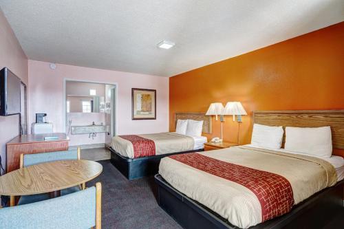 a hotel room with two beds and a table at Regency Inn in Fayetteville